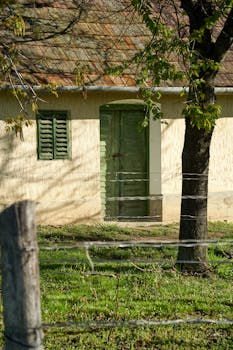 A picturesque rustic adobe house with green shutters and door in Türje, Hungary.