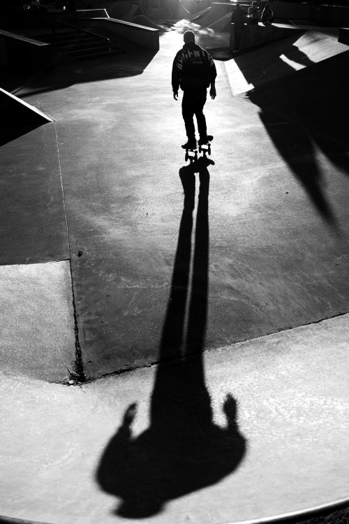 Free Black and white photo of a skateboarder casting a dramatic long shadow in Buenos Aires skate park. Stock Photo