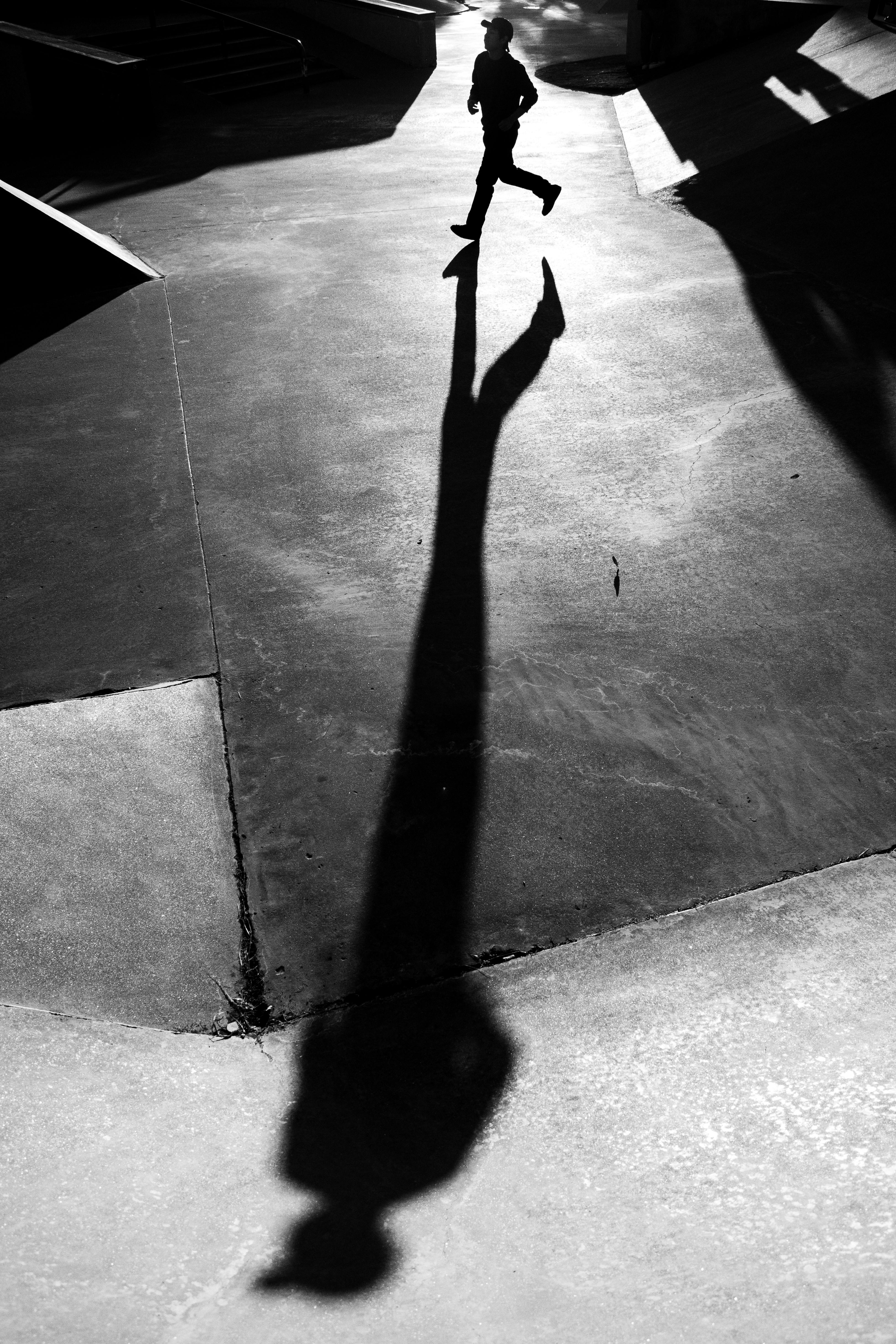 Free A striking silhouette of a person running on urban streets in black and white. Stock Photo