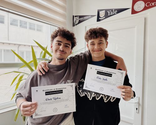 Free Two young adults proudly display their graduation certificates inside a classroom. Stock Photo