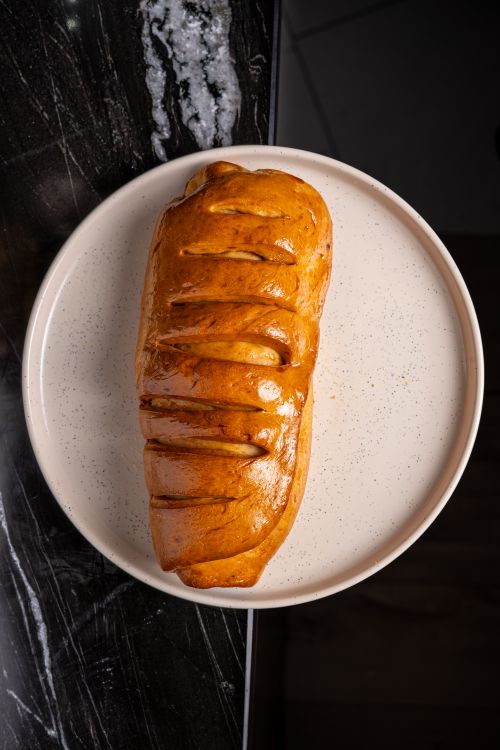 Free Close-up of a golden loaf of bread on a speckled plate, top view. Stock Photo