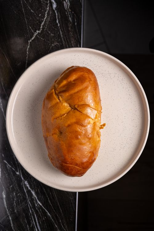 Free A top-down view of a freshly baked bread loaf on a white ceramic plate against a dark marble background. Stock Photo