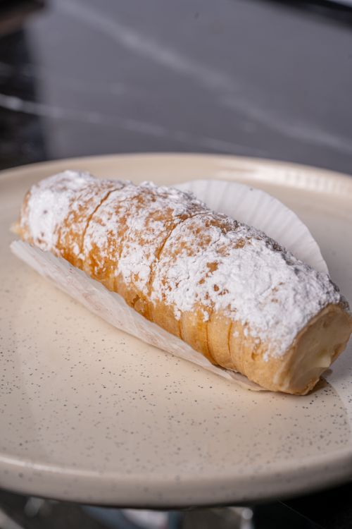 Free Close-up of a classic cream horn pastry with powdered sugar on a plate. Stock Photo