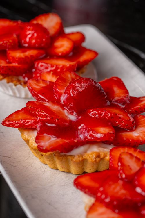 Free Enticing close-up of fresh strawberry tarts topped with glazed strawberries, perfect for dessert lovers. Stock Photo