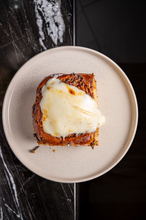 Free Appetizing cinnamon roll with creamy icing on a plate. Perfect breakfast or dessert. Shot indoors. Stock Photo