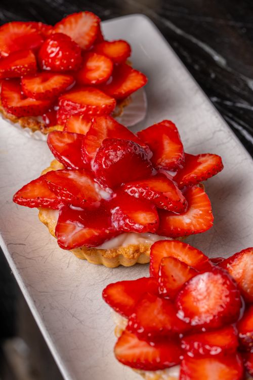Free Close-up of delectable strawberry tarts arranged on a textured platter, showcasing fresh and vibrant strawberries. Stock Photo
