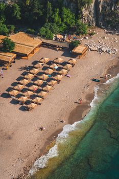 Scenic aerial view of a beach in Muğla, Türkiye with tiki huts and turquoise water.