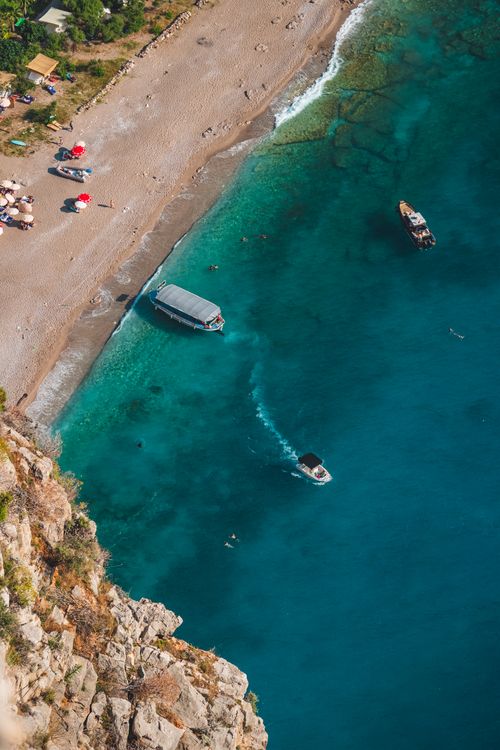 Free Stunning aerial shot of the picturesque coastline in Muğla, Türkiye with boats and swimmers. Stock Photo