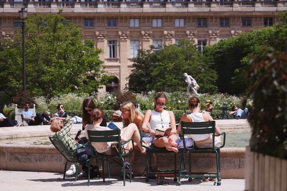 People enjoying leisure time at Jardin du Palais Royal, Paris on a sunny day.