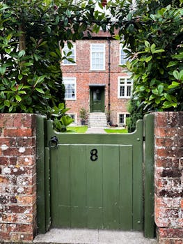 Beautiful green gate leading to a charming brick house in Salisbury, England.