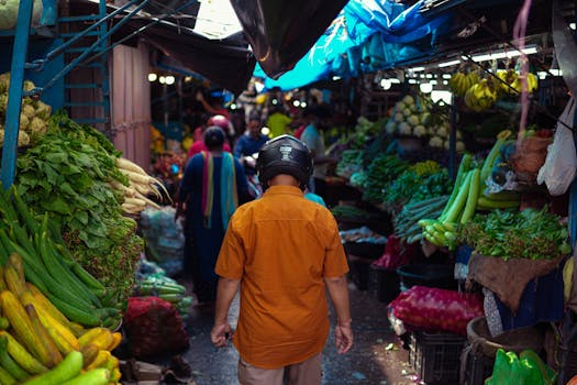 Crowded market with diverse vegetables and people shopping. Vibrant street life captured.