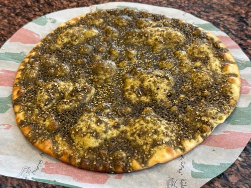 Free Close-up of a freshly baked za'atar flatbread on colorful patterned paper. Stock Photo