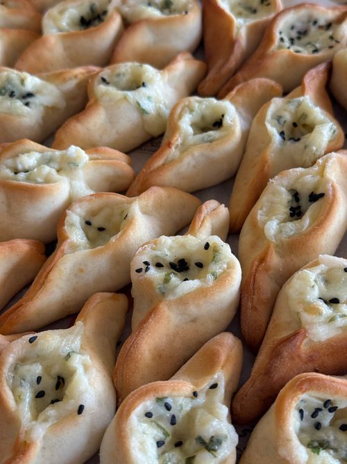 Free Close-up of freshly baked pastries filled with cheese and topped with seeds, displaying a golden crust. Stock Photo