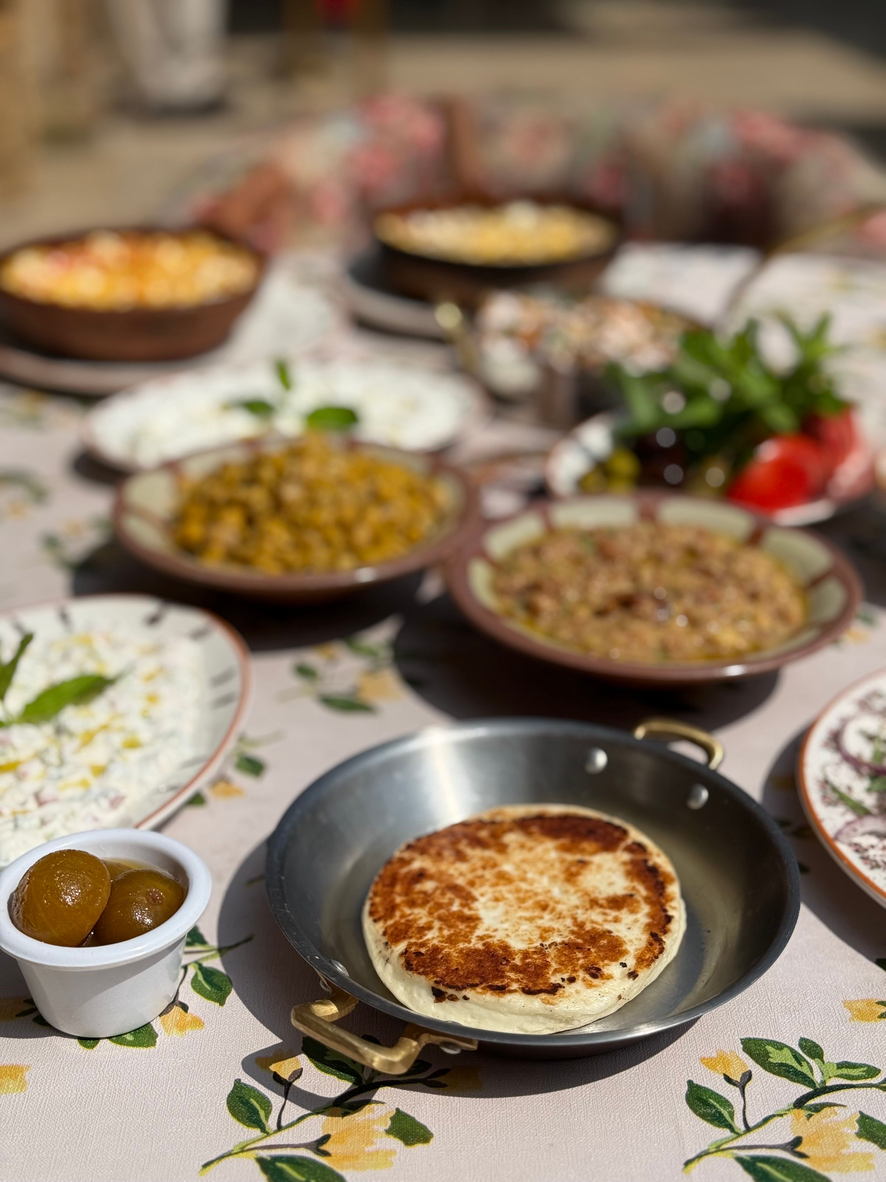 A mouthwatering traditional breakfast spread with fresh flatbread, legumes and garnishes.