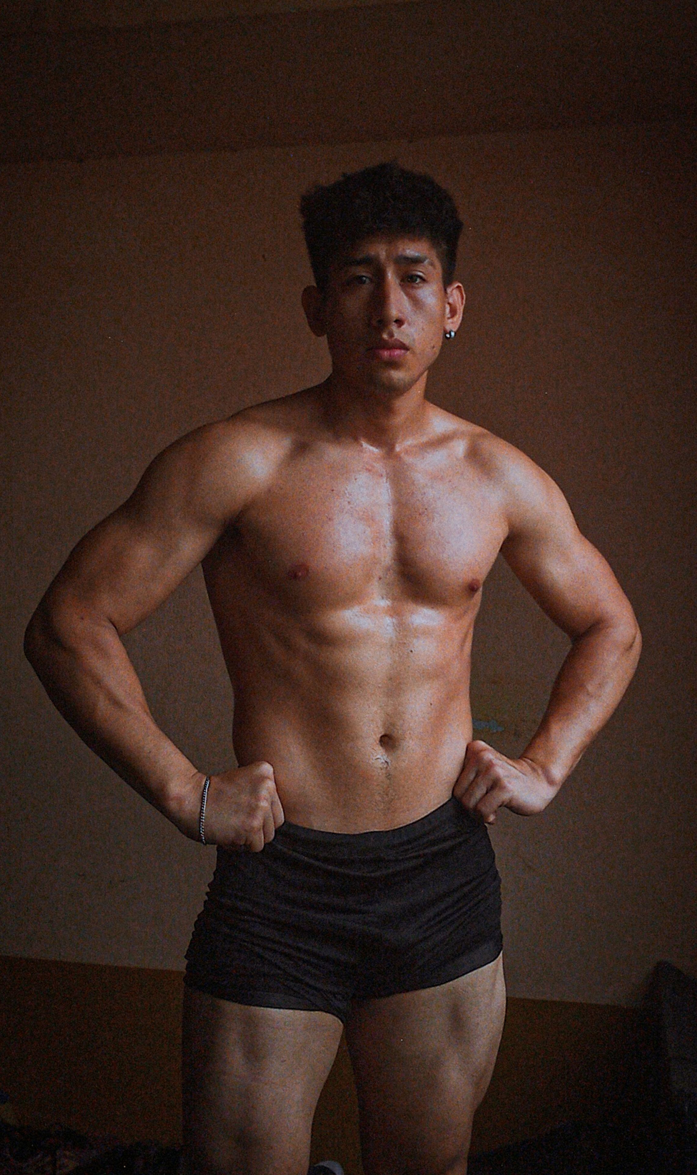 Muscular adult male posing confidently indoors, showcasing fitness and strength.