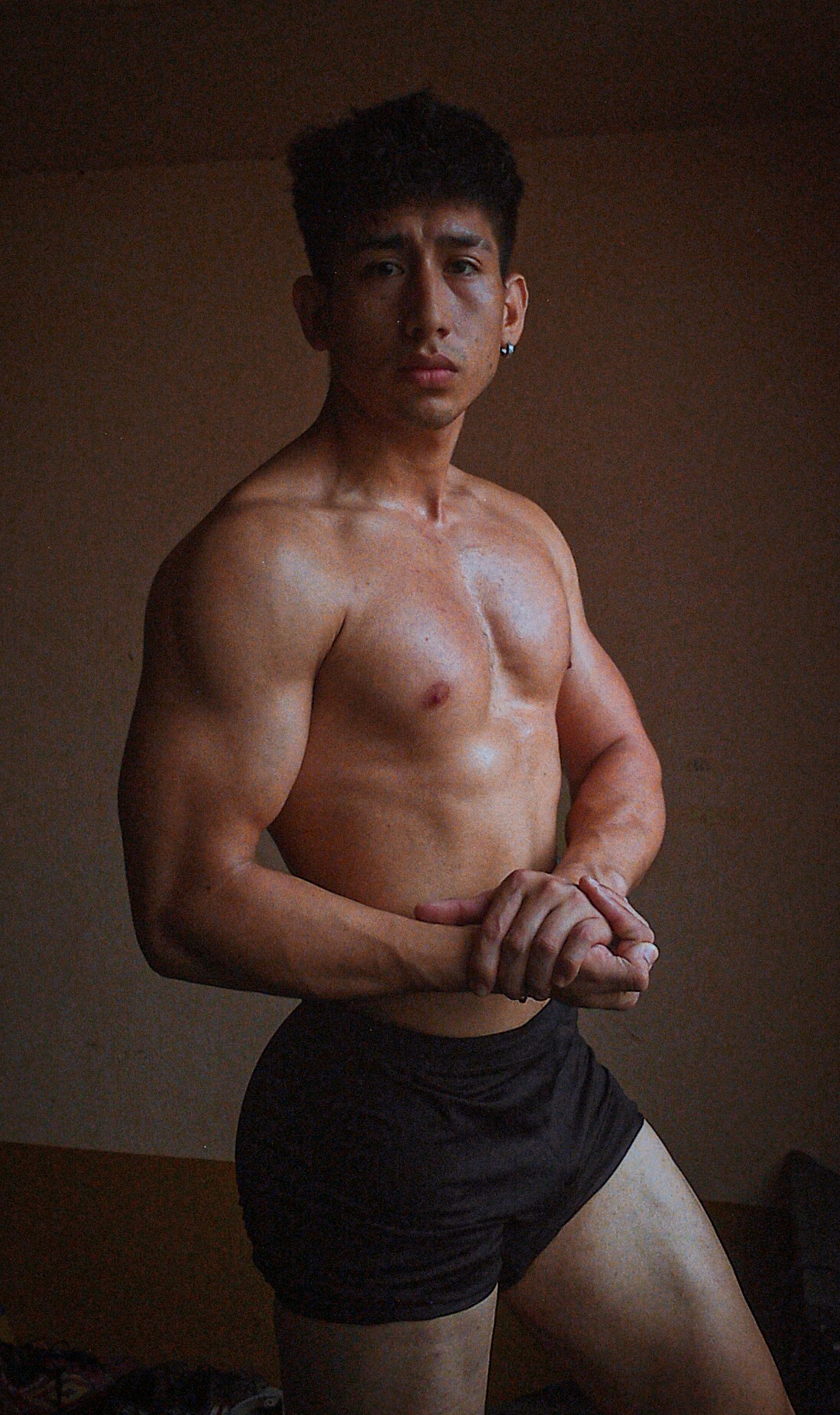 A fit, muscular man poses in soft natural lighting, showcasing strength and physique.