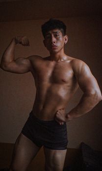 A muscular man flexing his arms indoors in Machala, Ecuador, showcasing strength and fitness.