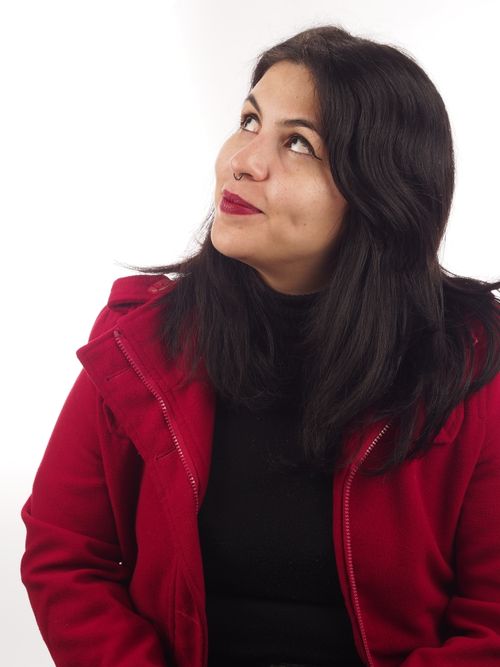 Free Woman in red coat looking up against white background. Stock Photo