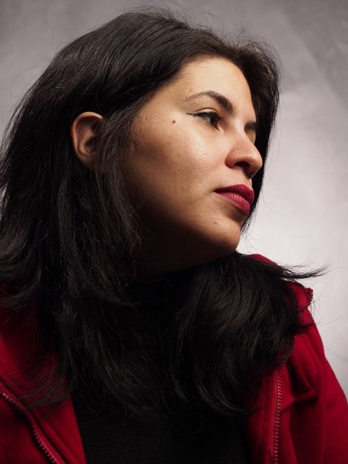 Free A contemplative profile portrait of a woman wearing a red jacket with a neutral background. Stock Photo