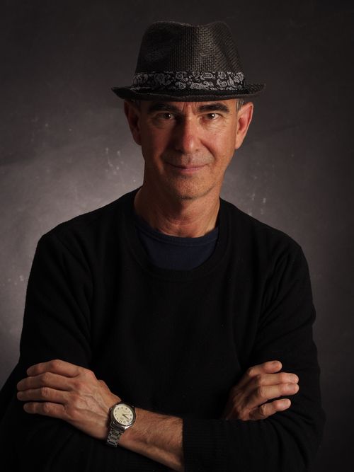 Free Confident man in a dark fedora, crossing arms, against a moody backdrop. Stock Photo