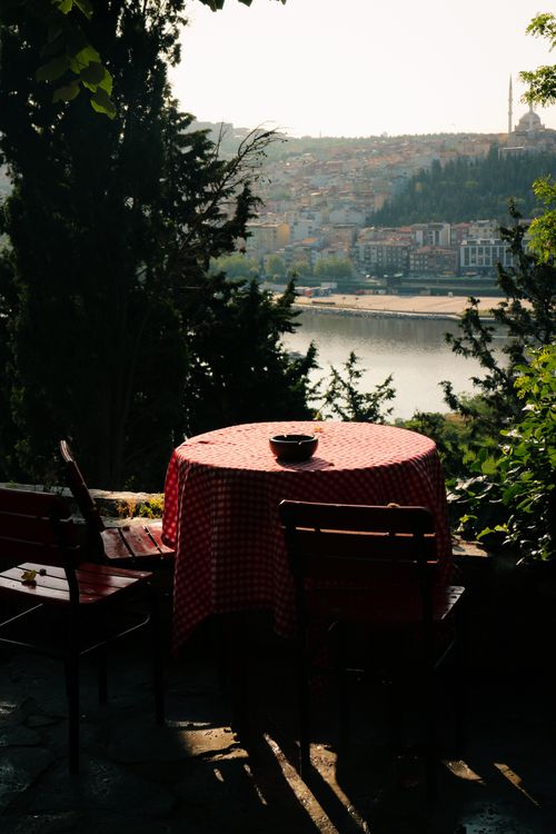 Free Charming outdoor cafe with red checkered tablecloth and river view, ideal for relaxation. Stock Photo