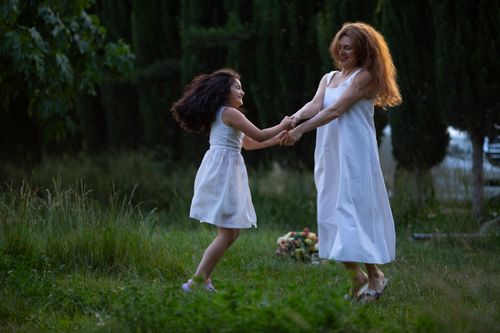 Free A joyful moment between mother and daughter dancing in an outdoor garden setting. Stock Photo