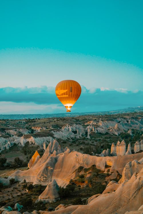 Free A vibrant hot air balloon floats over the rocky landscapes of Cappadocia at sunrise. Stock Photo