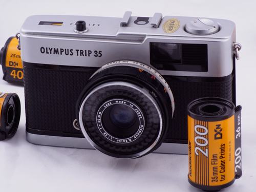 Free Classic Olympus Trip 35 film camera with Kodak film rolls, evoking photographic nostalgia. Stock Photo