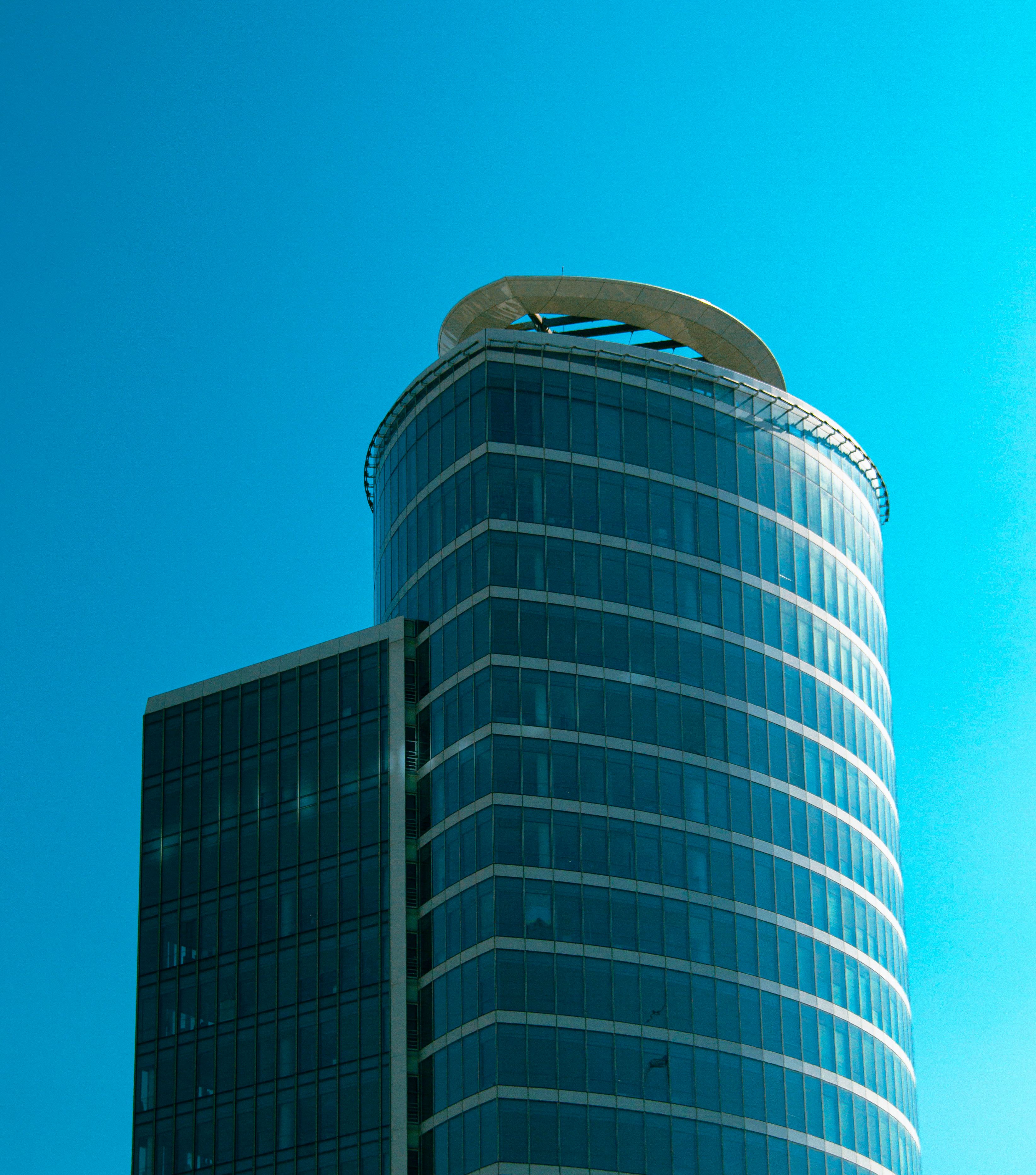 Tall modern skyscraper with glass facade under a bright blue sky, architectural elegance.