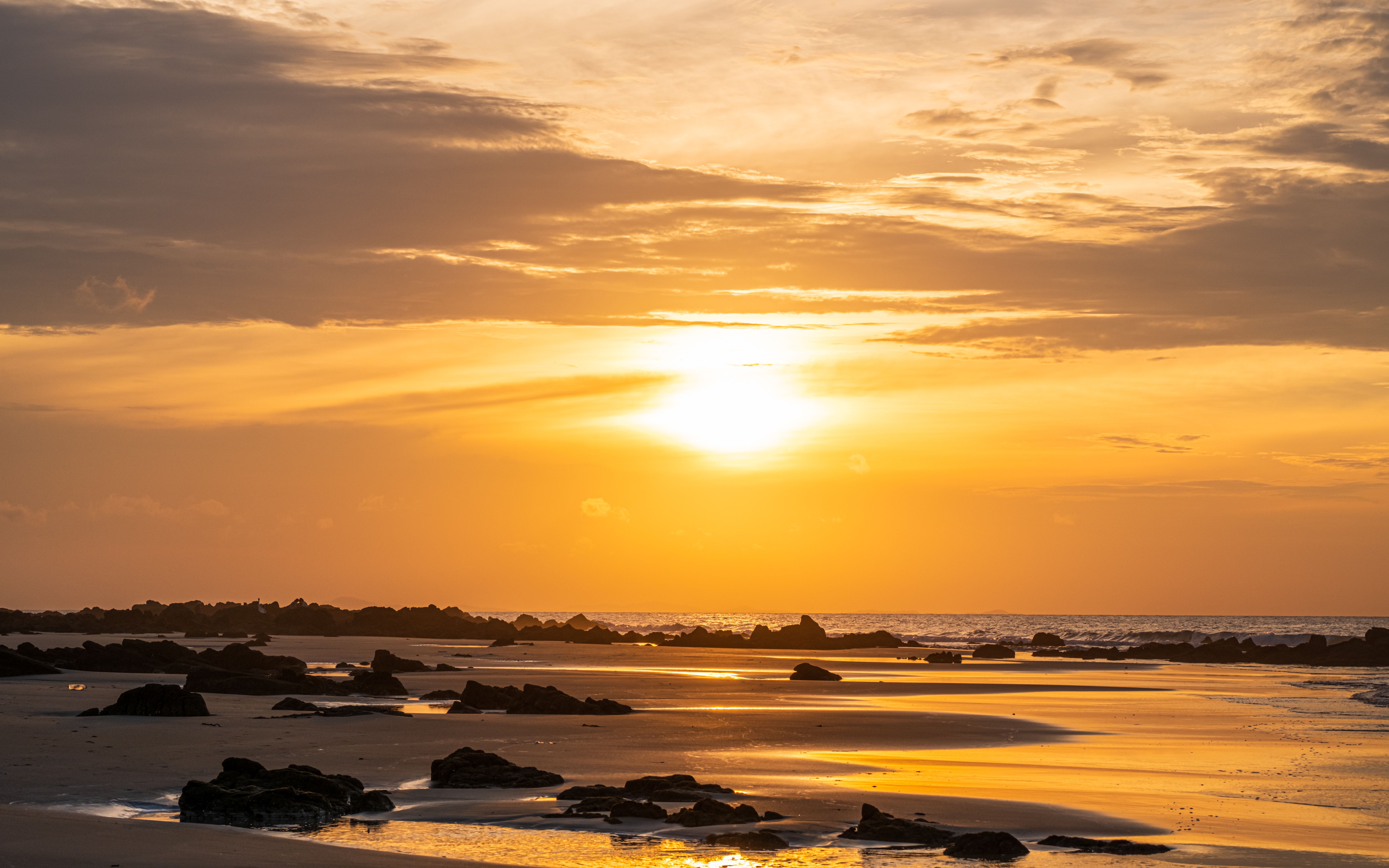 Serene Beach Sunset over Rocky Shoreline · Free Stock Photo