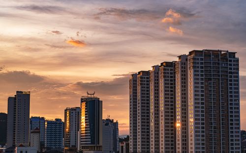 Free Urban skyline with tall buildings at sunset, reflecting warm colors in the sky. Stock Photo