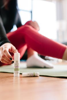Focused shot of a woman applying CBD balm during a yoga session indoors.
