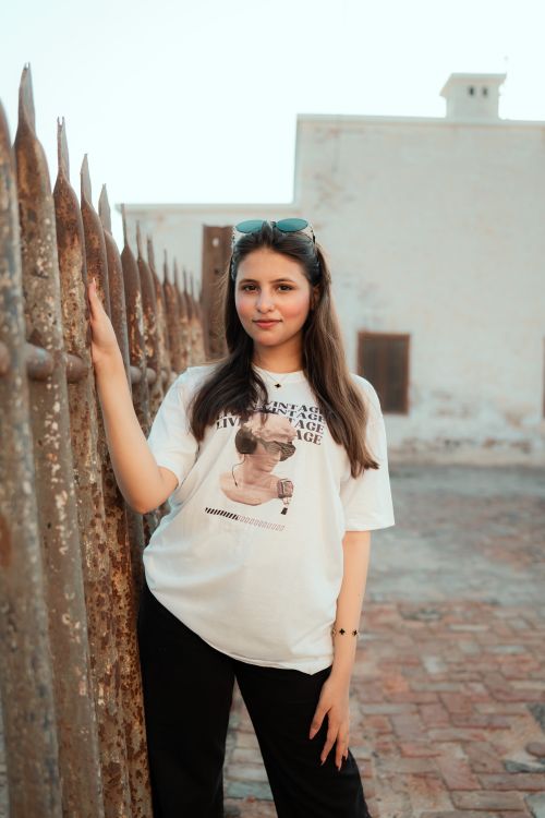 Free Stylish young woman posing outdoors by a rustic fence, exuding confidence and charm. Stock Photo