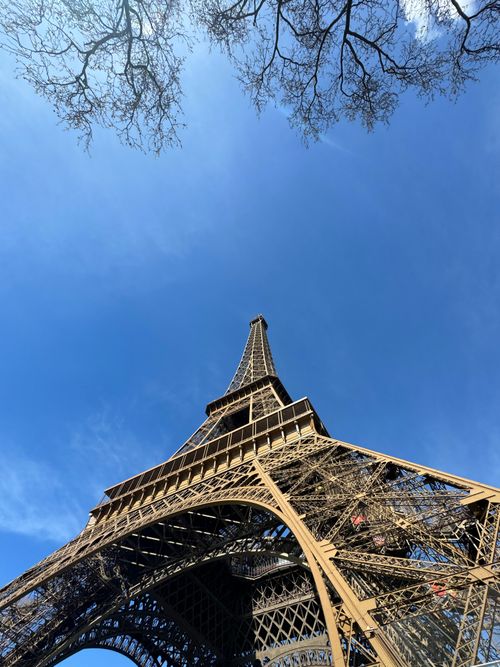 Free Low-angle view of the Eiffel Tower under a vibrant blue sky in Paris, France. Stock Photo