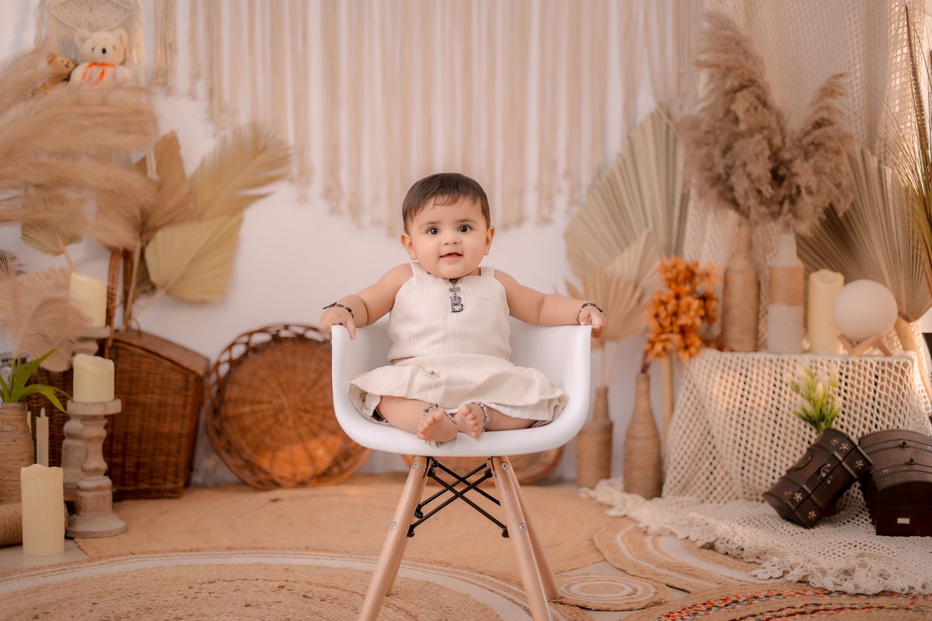 A cute baby sitting on a chair in a bohemian styled room with earthy decor.