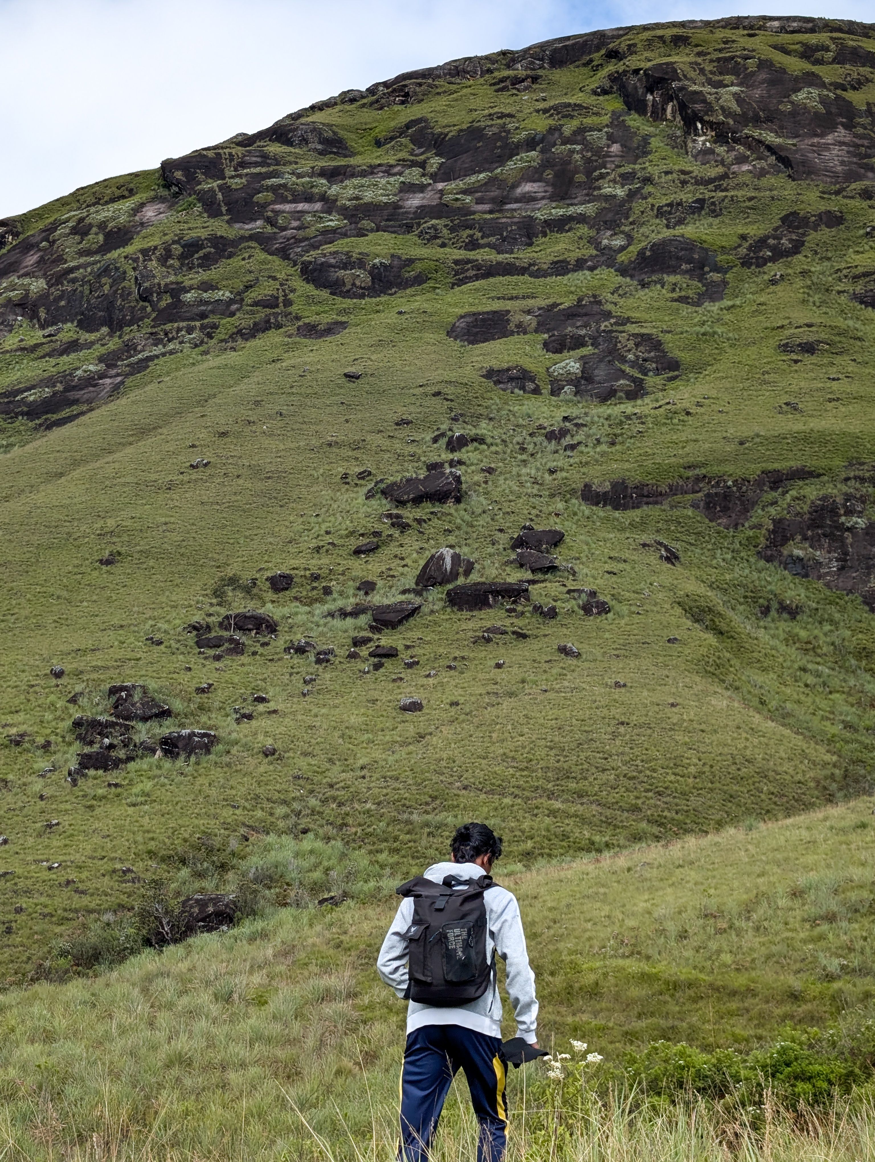 A lone hiker with a backpack walks through the lush green hills of Bogawantalawa, Central Province, Sri Lanka.