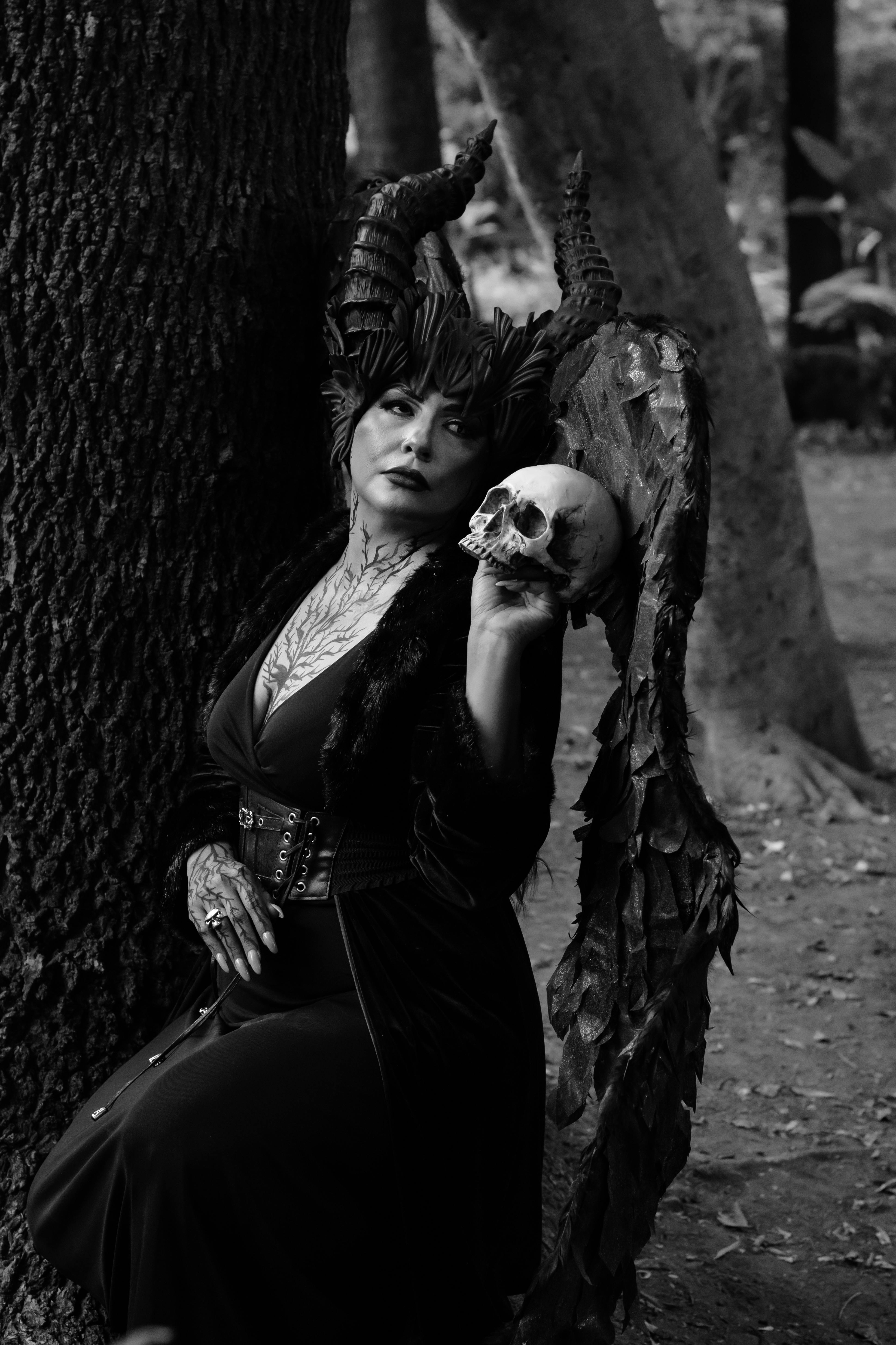 Gratuit Une femme en tenue gothique tient un crâne, entourée d'une atmosphère de forêt sombre. Photos