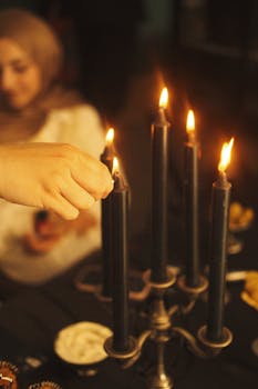 A hand lights black candles on an elegant candelabra, creating a cozy dinner atmosphere.