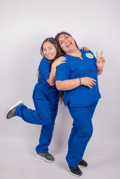Two happy nurses posing in blue scrubs, exuding positive energy and fun.