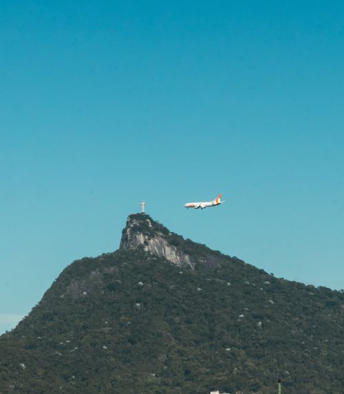 Free Airplane flying over Corcovado Mountain near Christ the Redeemer statue in Rio de Janeiro. Stock Photo