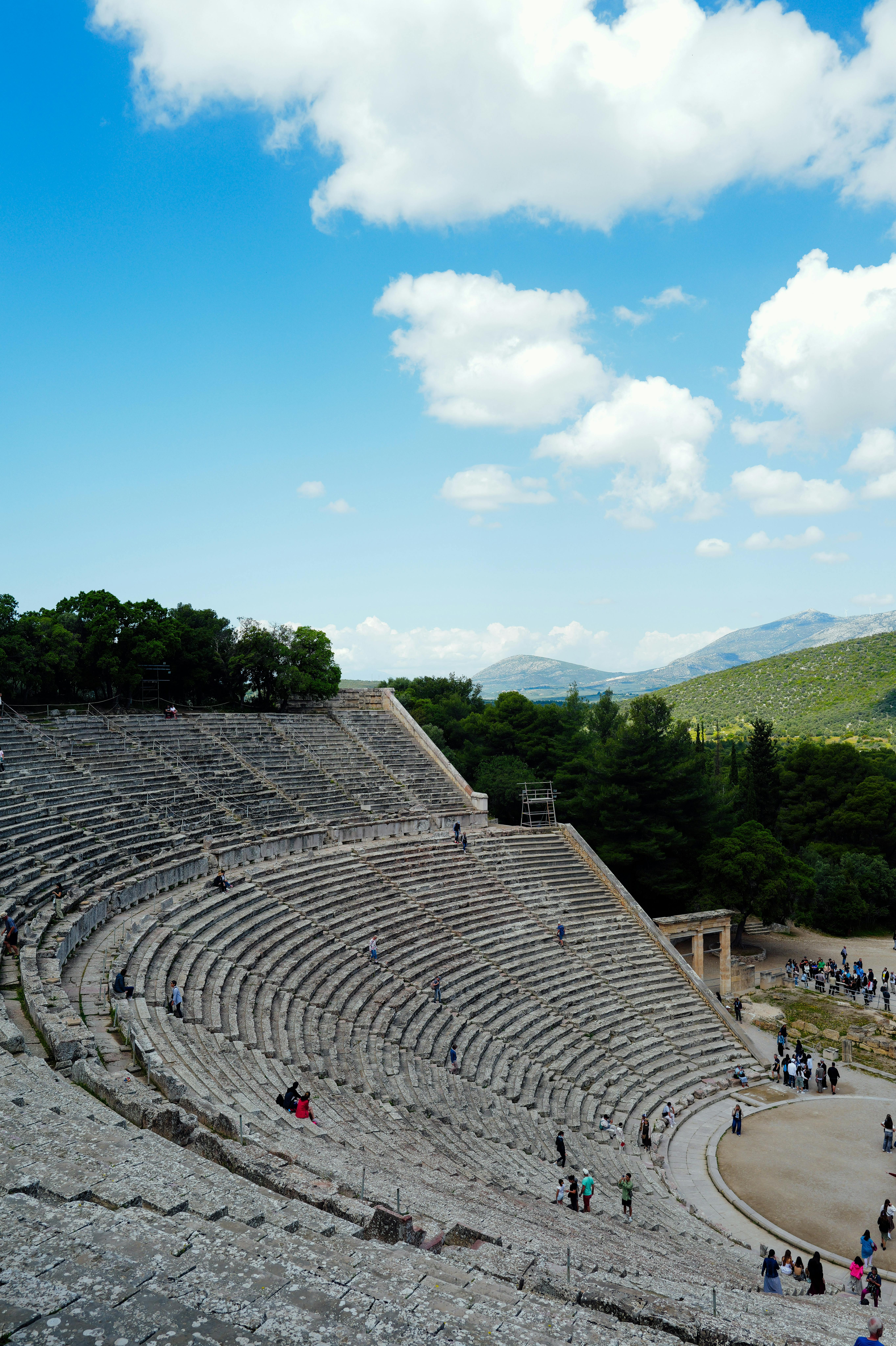 Gratis Vista panorámica del antiguo anfiteatro griego con cielos azules y exuberante vegetación. Foto de stock