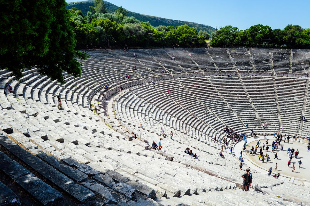 The great ancient theater of Epidaurus seen from the upper tiers, with visitors on the orchestra circle below