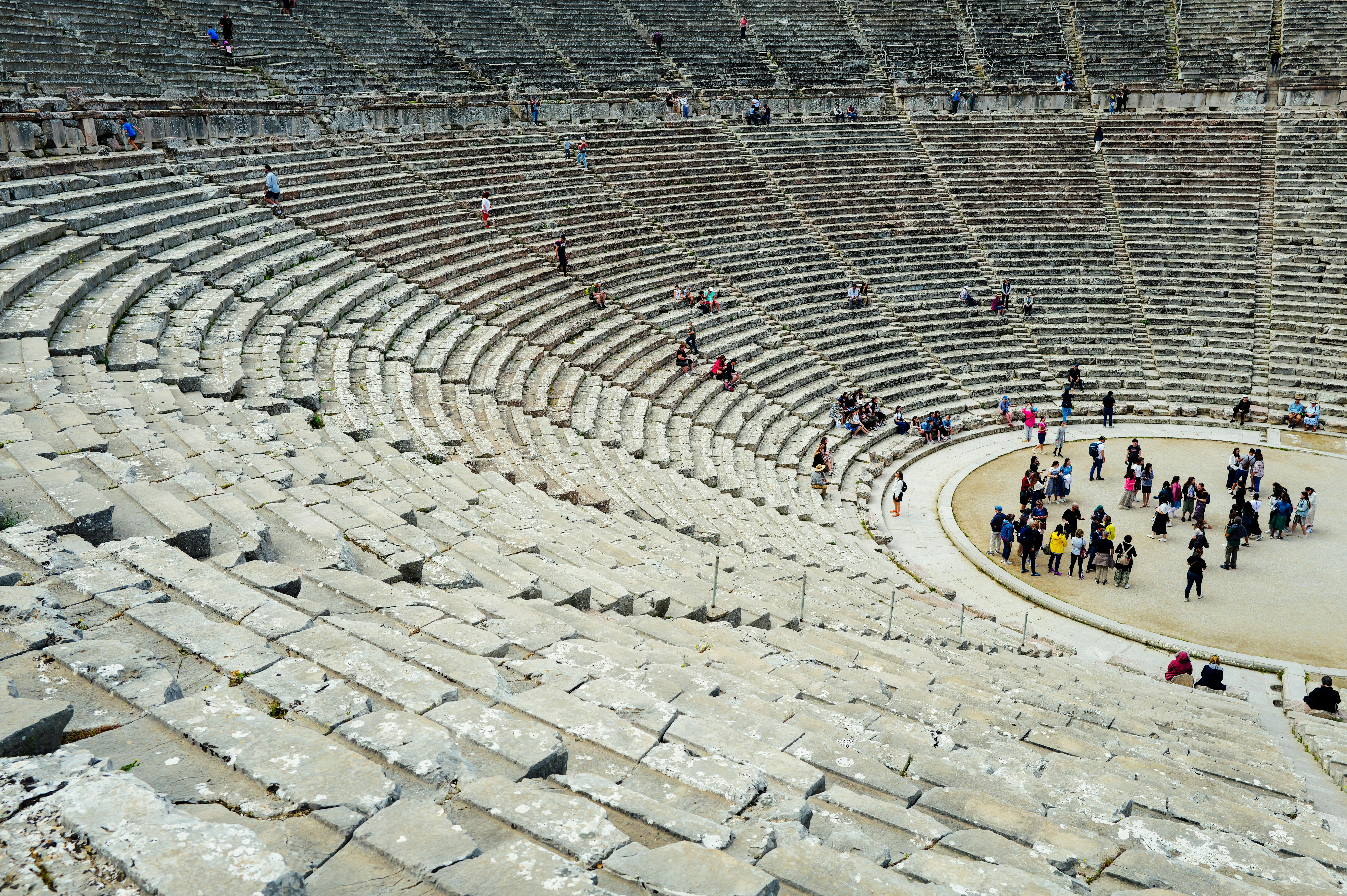 Free Tourists explore the ancient amphitheater showcasing historic architecture and cultural heritage. Stock Photo
