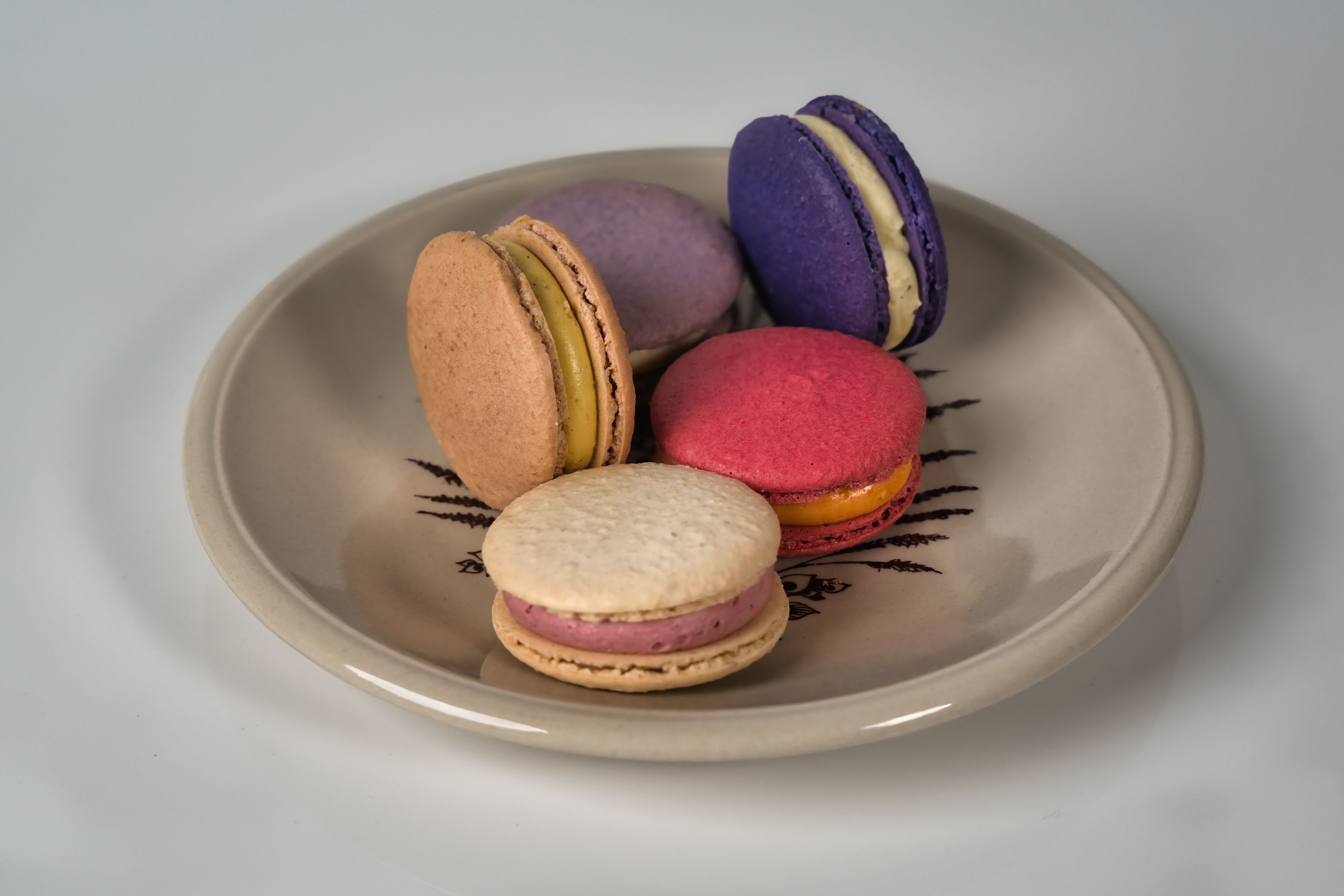 A close-up shot of assorted colorful French macarons on a decorative plate.