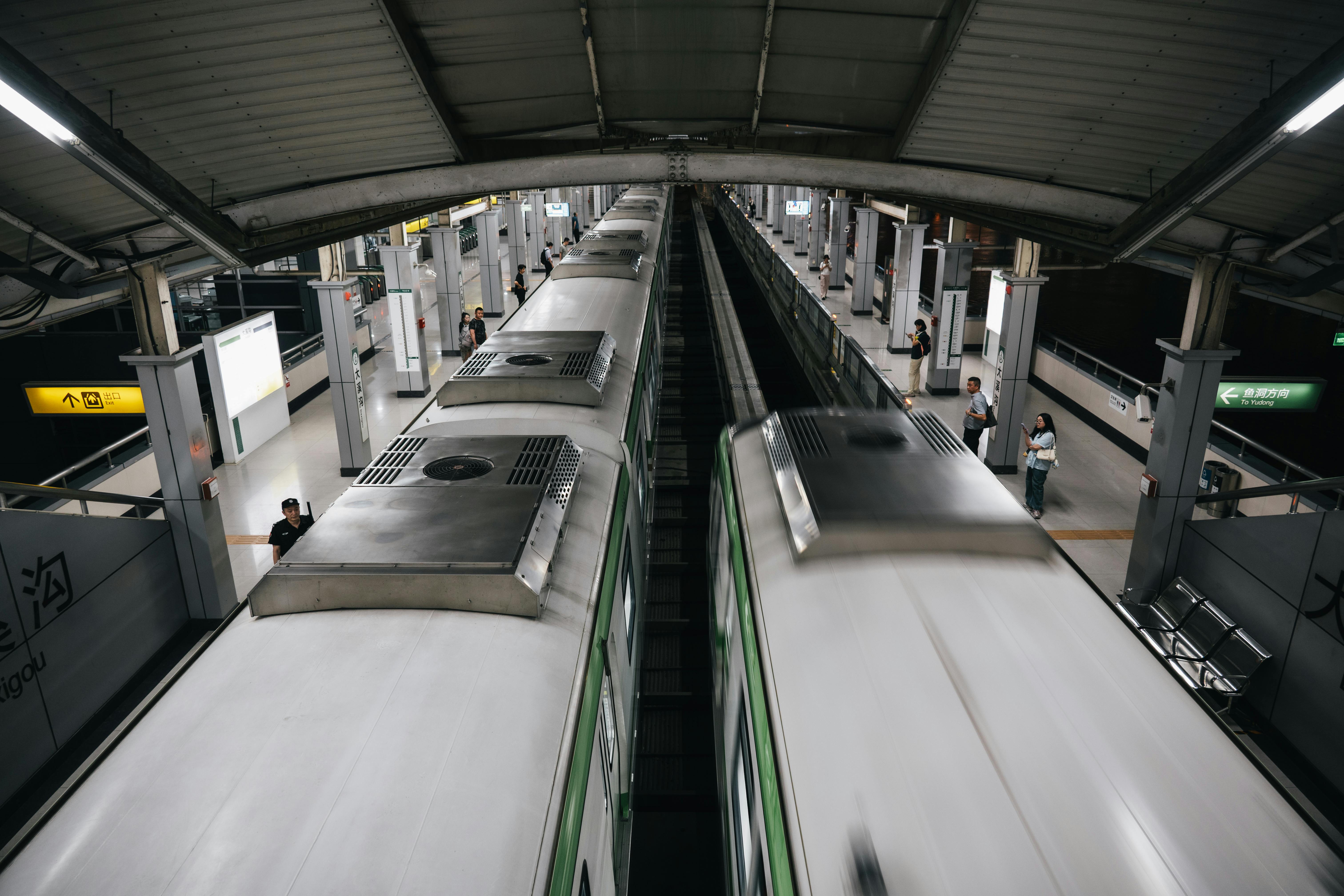 Dynamic view of a bustling subway station with trains in motion and passengers on the platform.