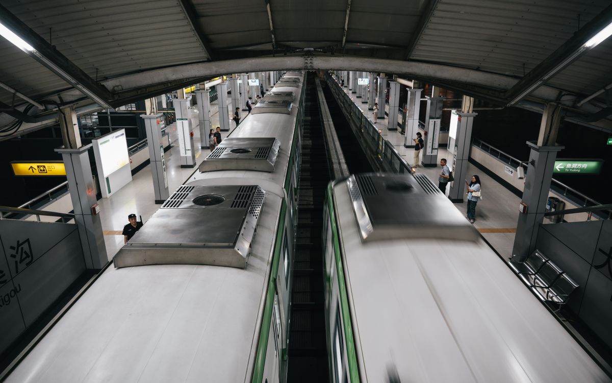 Dynamic view of a bustling subway station with trains in motion and passengers on the platform.