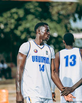 Two men playing outdoor basketball, wearing jerseys number 14 and 13.