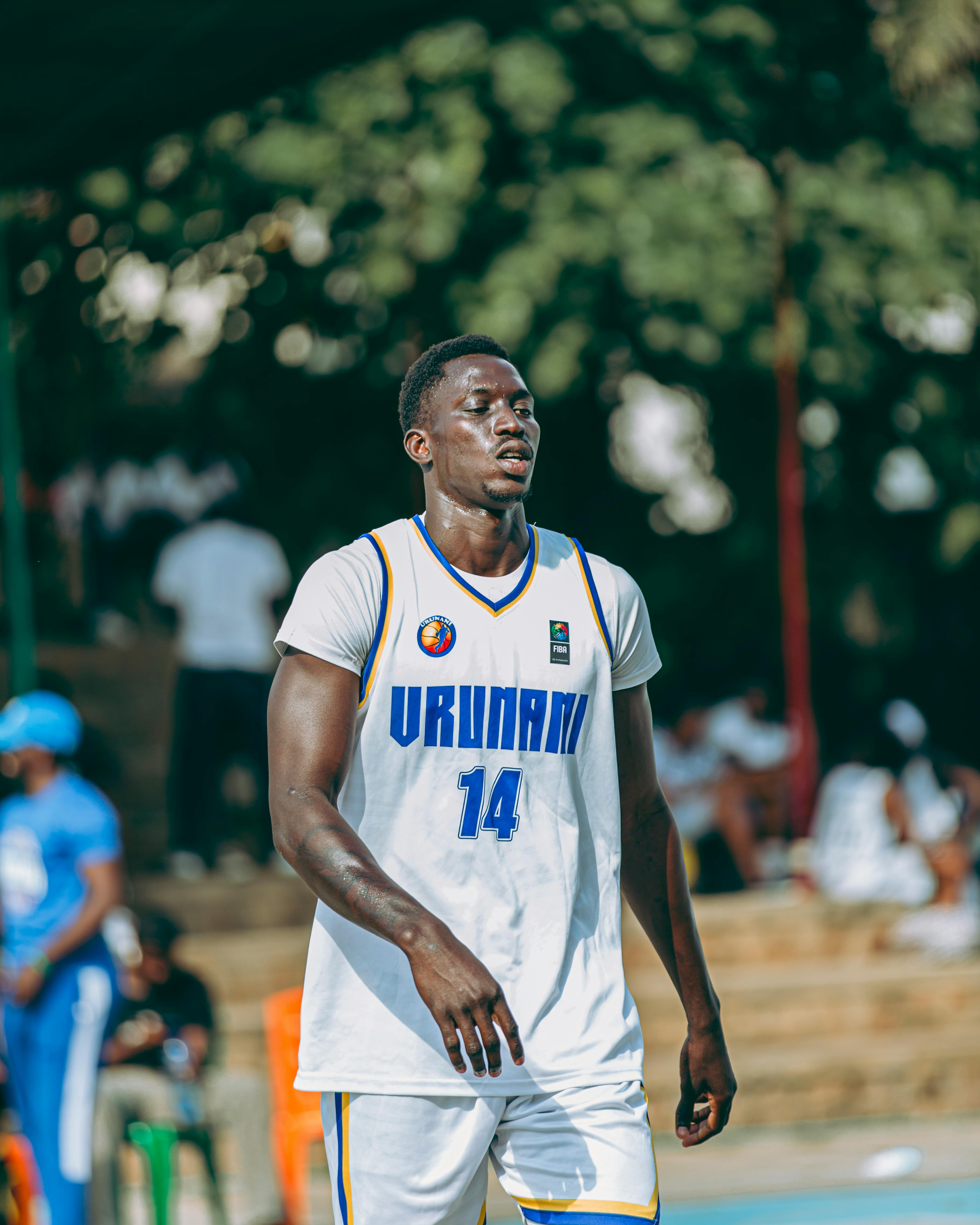 Athlete playing basketball outdoors in white URUNANI jersey.