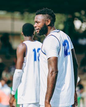 Two basketball players in uniforms outdoors during a game, focused and ready to compete.