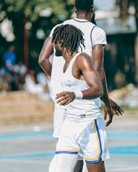 Two male athletes playing outdoor basketball on a sunny day.